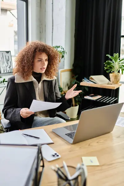 In a stylish office setting, a woman passionately discusses ideas while seated at her desk. — Stock Photo