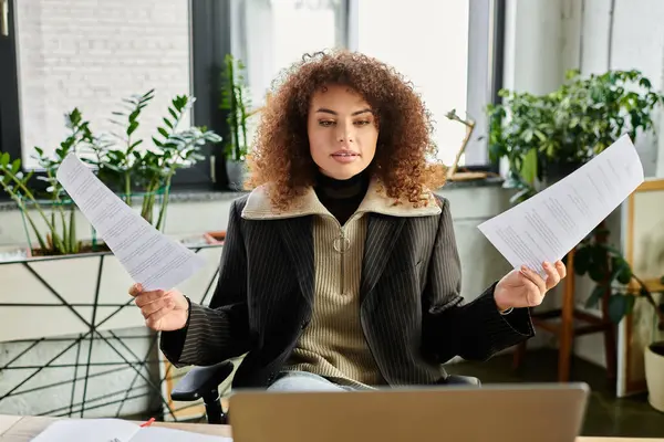 A focused woman analyzes important papers in her welcoming office filled with plants. — Stock Photo