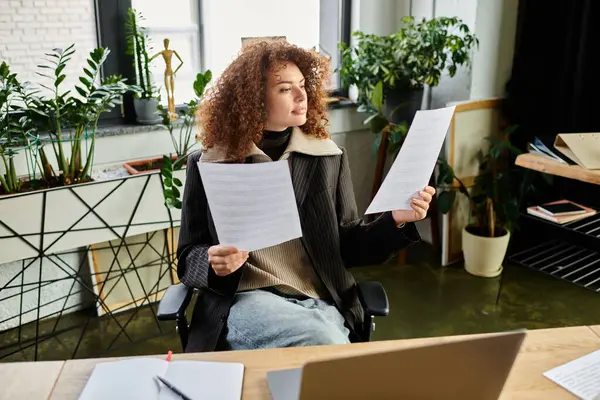 A woman examines two papers in her modern office filled with plants and natural light. — Stock Photo
