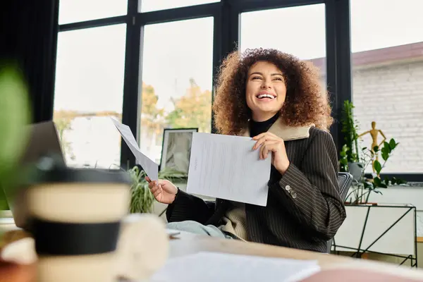 A woman beams with happiness while reviewing her documents in a modern workspace — Stock Photo