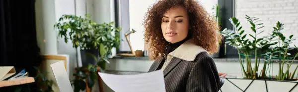 In a vibrant workspace, a woman examines important documents surrounded by greenery. — Stock Photo