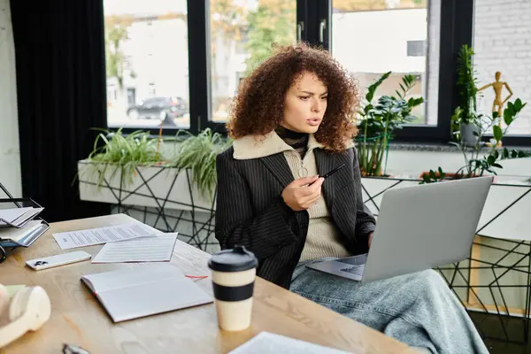 A woman collaborates and researches intently while seated at a stylish desk in a bright space. — Stock Photo