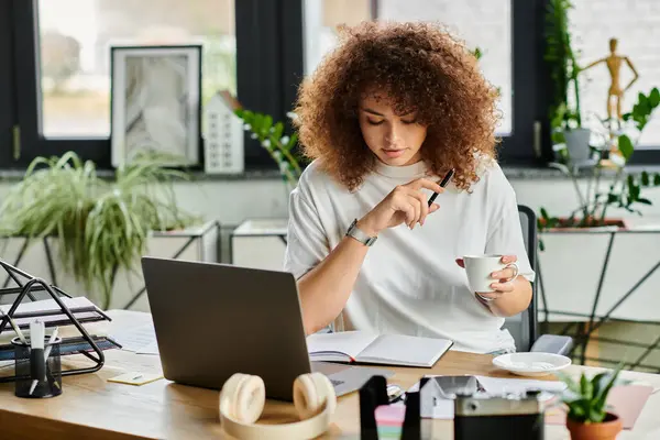 A woman contemplates her notes with a cup of coffee in a vibrant workspace filled with plants. — Stock Photo