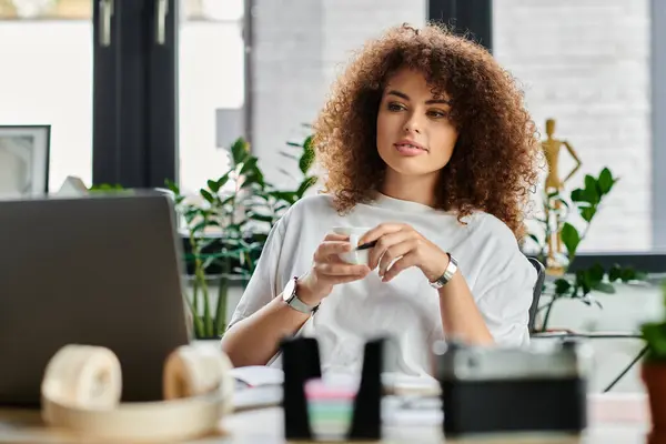 Una donna siede pensieroso alla sua scrivania, riflettendo mentre immerso nel verde e arredamento moderno. — Foto stock