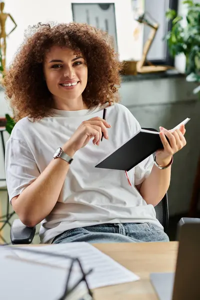 A joyful woman engages in creative writing at a stylish workspace filled with greenery. — Stock Photo