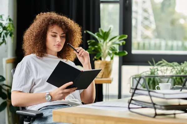 A woman sits quietly, pondering her notes while surrounded by plants in a cozy workspace. — Stock Photo