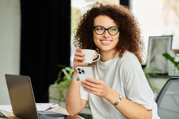 Relaxing in a stylish office, a woman drinks coffee and checks her smartphone with a smile. — Stock Photo