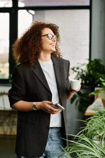 This woman smiles joyfully as she holds a cup of coffee and checks her phone in a cozy space. — Stock Photo