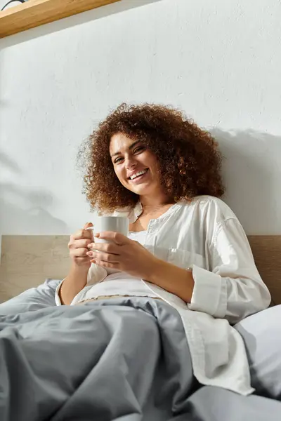The woman smiles warmly as she savors her drink in a comfortable setting. — Stock Photo