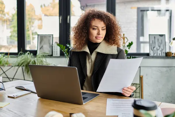 In a stylish office, a woman attentively examines important papers while seated at her desk. — Stock Photo