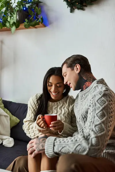 A couple cuddles together, sharing warmth and joy over hot cocoa in a festive atmosphere. — Stock Photo