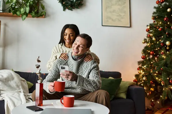 A couple smiles and sips warm drinks together, surrounded by festive decor. — Stock Photo