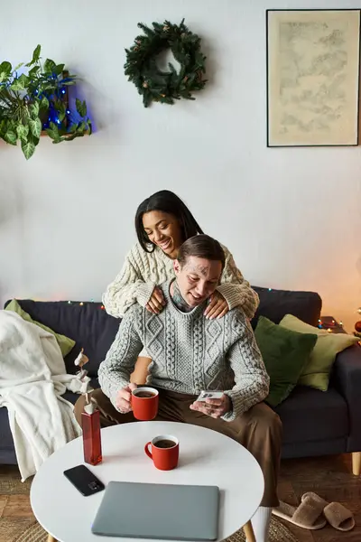 A loving couple enjoys time together at home, celebrating Christmas with cozy drinks and joy. — Stock Photo