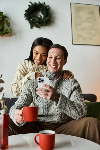A couple enjoys each others company while sipping hot drinks and smiling together at home. — Stock Photo