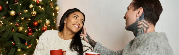 A couple enjoys a warm moment at home, sharing smiles and hot beverages during Christmas. — Stock Photo