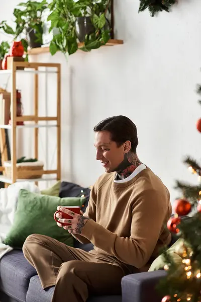 A man at home, savoring holiday drink and festive decorations. — Stock Photo