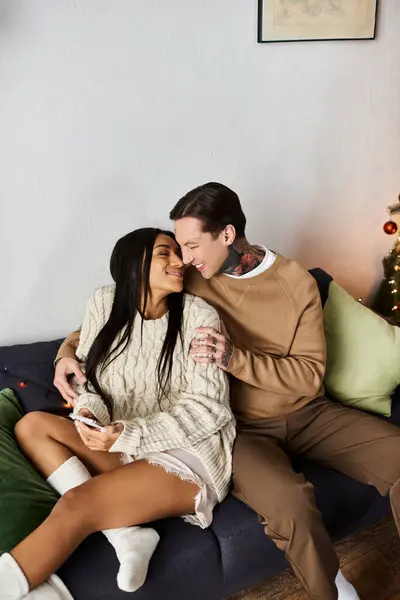 A couple enjoys each others company cuddled on a couch, surrounded by festive decor. — Stock Photo