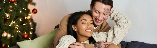 A happy couple embraces warmly, surrounded by cozy holiday decorations and love. — Stock Photo