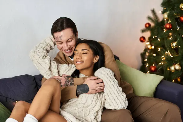 A couple enjoys each others company by the Christmas tree, radiating love and warmth. — Stock Photo