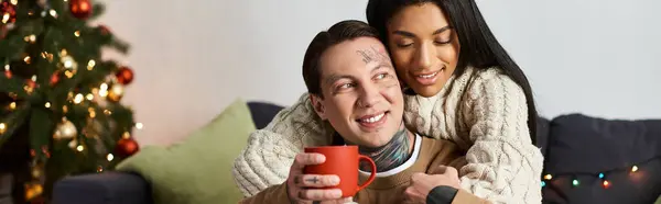 A couple enjoys each others company, cozying up with drinks in a festive home setting. — Stock Photo