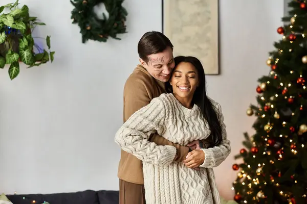 A joyful couple shares a warm embrace, celebrating the love of Christmas together at home. — Stock Photo