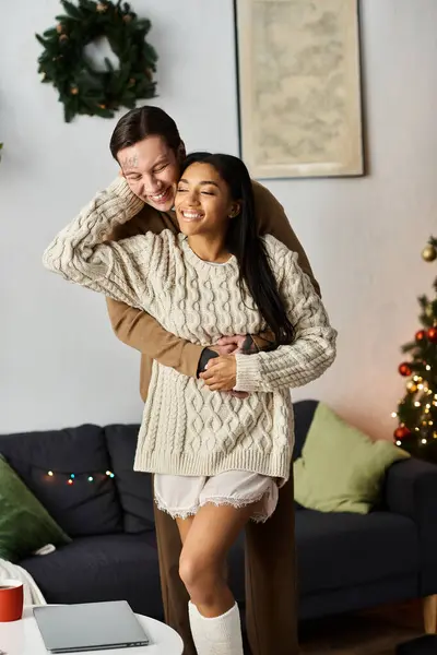 A joyful couple embraces in their cozy, Christmas decorated living room. — Stock Photo