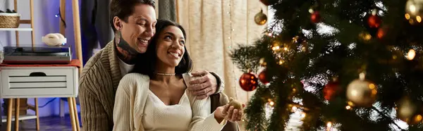 Un couple aimant partage sourires et chaleur dans leur maison pendant qu'ils apprécient l'esprit de Noël ensemble. — Photo de stock