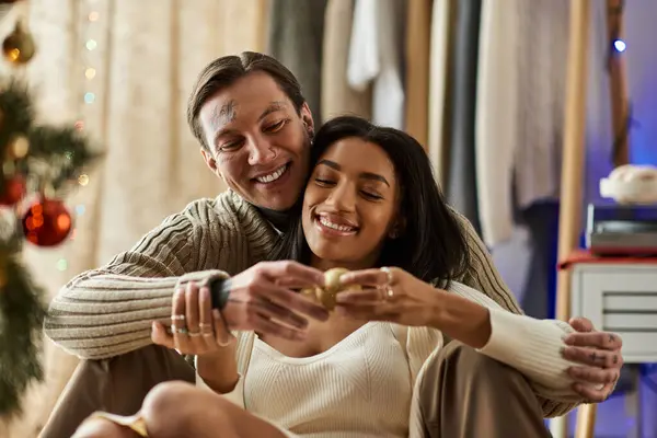 A loving couple shares a warm Christmas moment, exchanging joy and tenderness in their cozy home. — Stock Photo