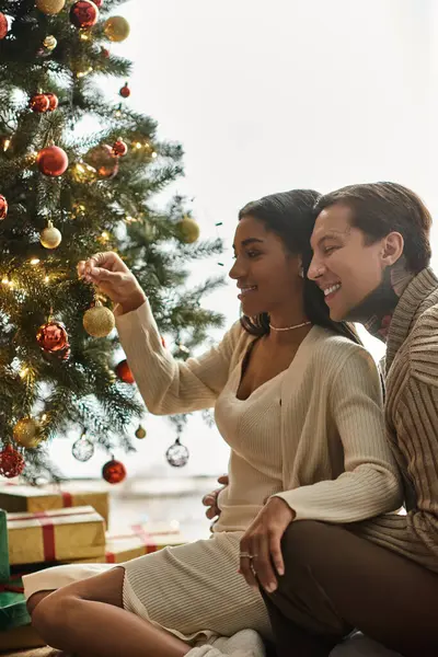 A loving couple enjoys decorating their Christmas tree at home, celebrating the festive season. — Foto stock