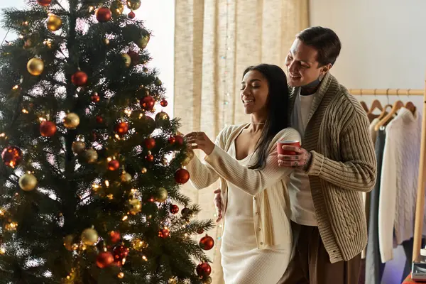 A loving couple shares a magical moment while decorating their Christmas tree at home. — Stock Photo