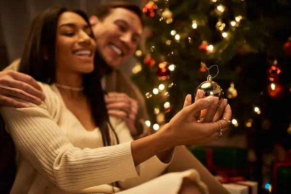 A loving couple shares a moment of joy while decorating their Christmas tree at home. — Stock Photo