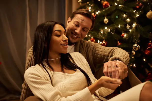 A couple enjoys a cozy moment together during the Christmas season, embracing the warmth of home. — Stock Photo