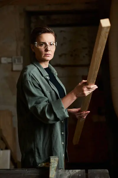 In a cozy workshop, a dedicated carpenter measures a piece of wood, embodying skill and craftsmanship. — Stock Photo