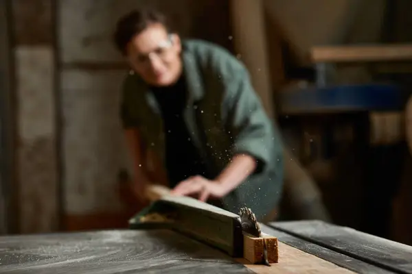 A focused carpenter is expertly working on wood, surrounded by tools in a cozy workshop atmosphere. — Stock Photo