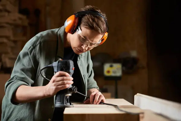 A dedicated carpenter meticulously carves wood, showcasing craftsmanship in her busy workshop environment. — Stock Photo