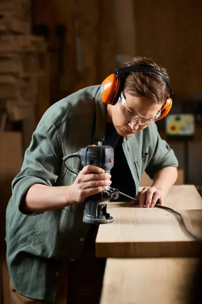 Une menuisière habile sculpte du bois avec un routeur dans son atelier, mettant en valeur son savoir-faire. — Photo de stock