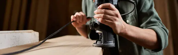 Un falegname donna focalizzata utilizza un router su legno, plasmando materiali nel suo luminoso laboratorio pieno di strumenti. — Foto stock