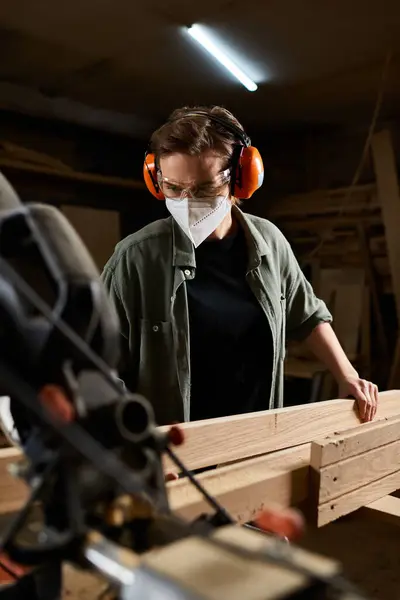 A focused female carpenter meticulously works with wood, showcasing her craftsmanship in a vibrant workshop. — Stock Photo