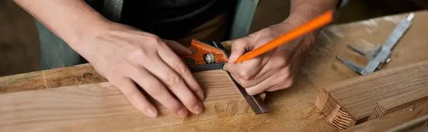 A female carpenter uses a square and pencil to mark precise measurements on a wooden plank in her workshop. — Stock Photo