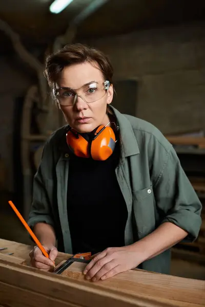 Un abile falegname si concentra intensamente mentre misura il legno in un laboratorio ben attrezzato, mettendo in mostra l'artigianato. — Foto stock