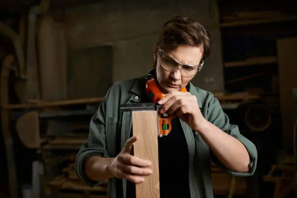 Una experta carpintera comprueba meticulosamente las medidas de madera en su animado taller. - foto de stock