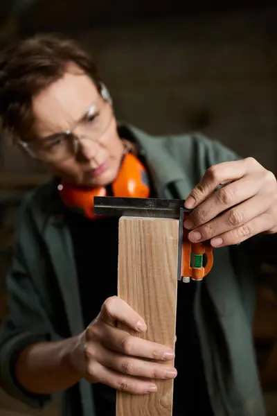 A dedicated carpenter focuses intently on measuring wood accurately, showcasing craftsmanship and skill. — Stock Photo