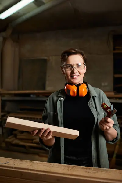 A skilled carpenter passionately works with wood, showcasing her craftsmanship in a lively workshop. — Stock Photo