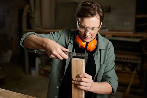 A skilled carpenter meticulously measures wooden planks in her well-equipped workshop, showcasing craftsmanship. — Stock Photo