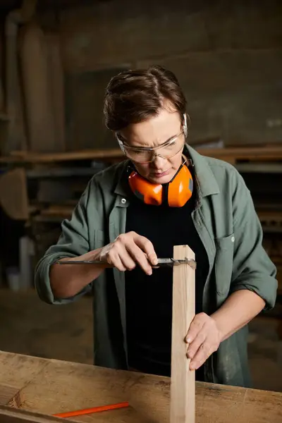A skilled carpenter focuses intently while working with wood in a vibrant workshop filled with tools. — Stock Photo