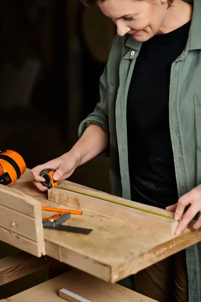 The carpenter focuses intently as she measures wood, showcasing her craftsmanship and dedication. — Stock Photo