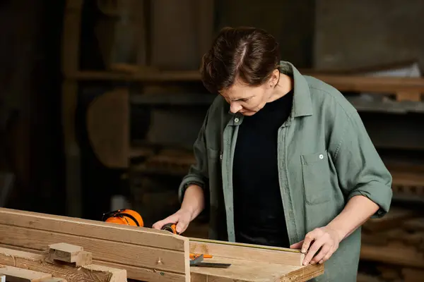 A skilled female carpenter carefully measures wood, demonstrating craftsmanship in her workshop environment. — Stock Photo