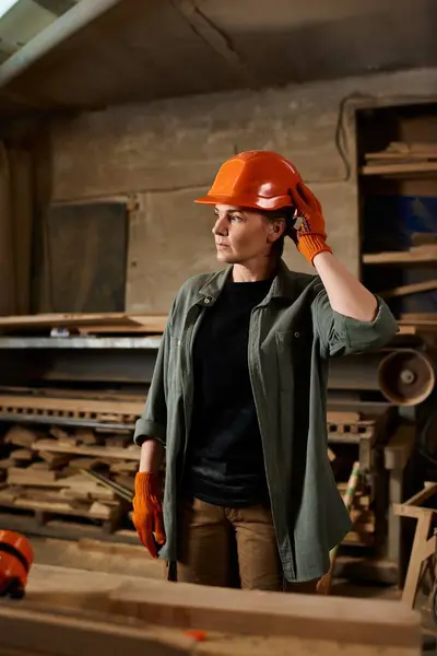 A skilled female carpenter stands confidently in her workshop, ready to create unique wooden pieces. — Stock Photo