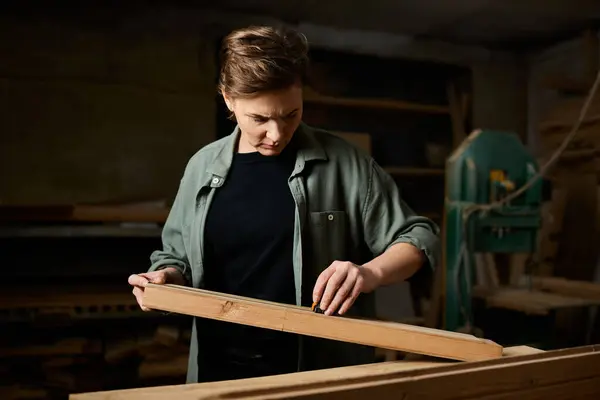 A skilled female carpenter focuses on precise measurements while working with timber in her workshop. — Stock Photo