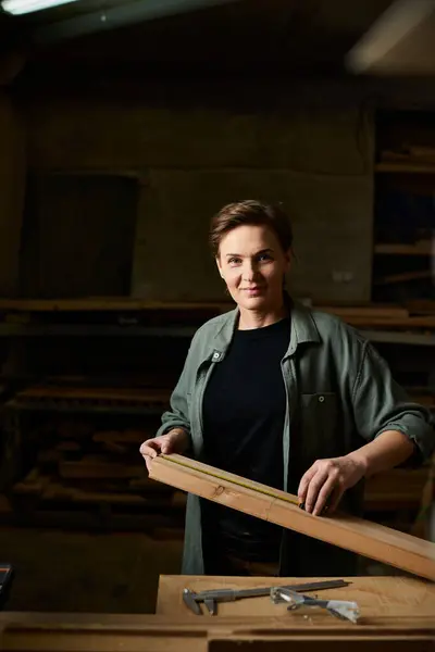 A talented woman carpenter focuses on her craft, shaping wood in a bright workshop filled with tools. — Foto stock